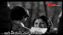 a black and white photo of a man giving a letter to a woman in telugu .