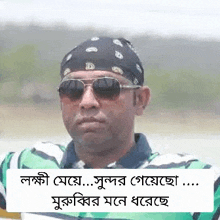 a man wearing sunglasses , a bandana and a green and white striped shirt .