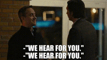 two men are standing next to each other and one of them is saying `` we hear for you . ''