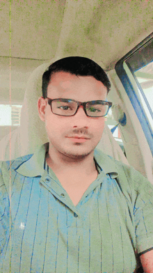 a man wearing glasses and a striped shirt takes a selfie