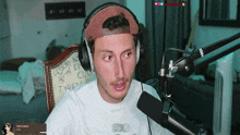 a man wearing headphones sits in front of a rode brand microphone