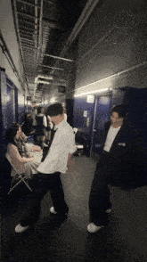 a man in a white shirt with the word nct on it stands in a hallway