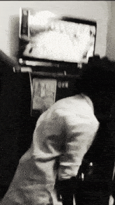 a black and white photo of a person in front of a television