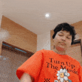a person is wearing an orange shirt that says turn up the music