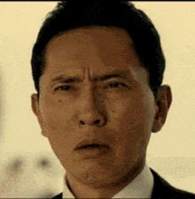 the man is wearing a suit and tie and making a funny face .