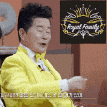 a man wearing a yellow suit and bow tie is sitting in front of a sign that says royal family