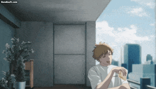 a man sits on a balcony eating a piece of bread with bandsoft.com written on the bottom right