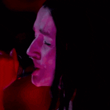 a woman is singing into a microphone in front of a red background