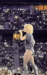 a woman in a leotard is singing into a microphone on a stage in front of a crowd .