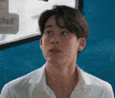 a young man in a white shirt is sitting on a blue bus looking up .