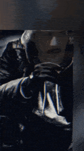 a man with a mustache is wearing a black leather jacket and black gloves