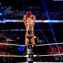 two women are wrestling in a wrestling ring while a crowd watches .