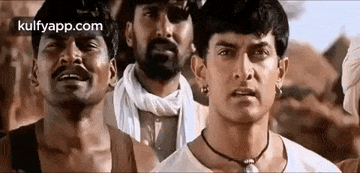 a group of men are standing next to each other looking at the camera .