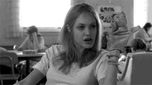 a black and white photo of a woman sitting in a classroom holding a puppet .