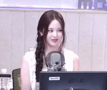 a woman is sitting in front of a microphone in front of an lg computer monitor .