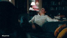 a man is laying on a couch with the hashtag #superman in the corner