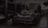 a silver sports car is parked in a garage next to a man .