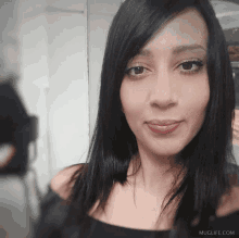 a woman taking a picture of herself with muglife.com in the lower right corner