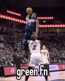 a basketball player is jumping in the air to catch a basketball while another player tries to stop him .