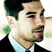 a man with a beard wearing a suit and tie smiles