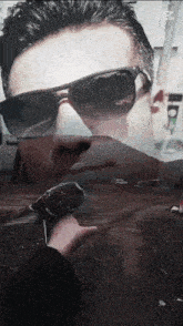 a man wearing sunglasses is holding a microphone in his hand