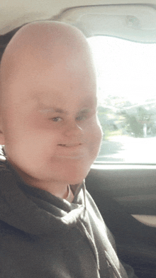 a man with a very large head is sitting in the back seat of a car