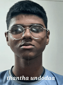 a young man wearing glasses and a blue shirt with the words thantha undodaa on the bottom