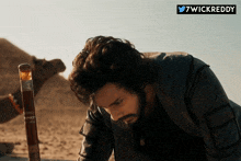 a man with a beard is kneeling down in front of a camel and a sign that says 7wickreddy on it