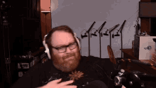 a man with a beard wearing headphones and glasses looks at the camera