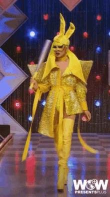 a woman in a yellow outfit is holding a bat and wow presents plus is on the bottom right