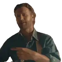 a man with a beard wearing a denim shirt is pointing at something