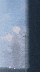 a blurred picture of a cloudy sky with a light pole in the foreground