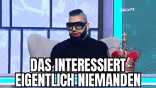 a man with a beard and red lips is wearing a crown and sunglasses .