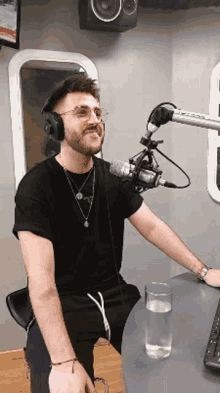 a man wearing headphones and glasses is sitting in front of a microphone