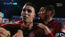two soccer players are hugging each other during a game that is sponsored by canal + sport