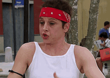 a woman wearing a white tank top and a red bandana with the letter e on it