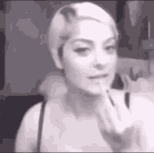 a black and white photo of a woman applying lipstick .