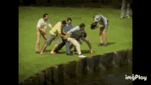 a group of men are standing around a man on a golf course while a cameraman takes a picture .
