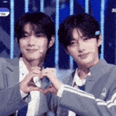 two young men are making a heart with their hands
