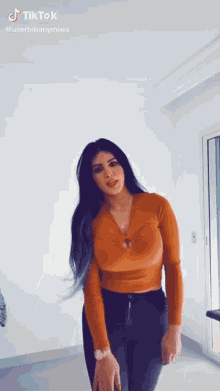 a woman in a crop top and black pants is standing in a room .