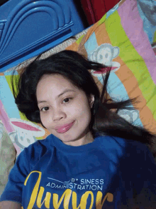 a woman laying on a bed wearing a blue shirt that says " administration business "
