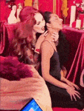 a woman is kissing another woman on the neck while sitting on a bed .