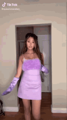 a woman in a purple dress and gloves is dancing .