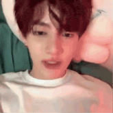 a close up of a person 's face with a pink pillow in the background