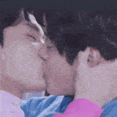 a couple of young men are kissing each other .