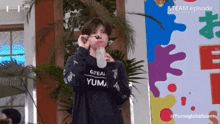 a person wearing a shirt that says yuma is drinking from a bottle