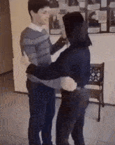 a man and a woman are hugging each other in a room
