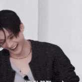 a man wearing a sweater and a necklace is laughing and smiling .