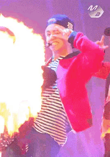 a man in a red jacket is holding a microphone while flames are coming out of his mouth