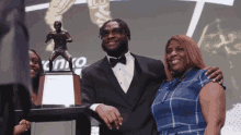 a man in a tuxedo is posing for a picture with a woman and a trophy